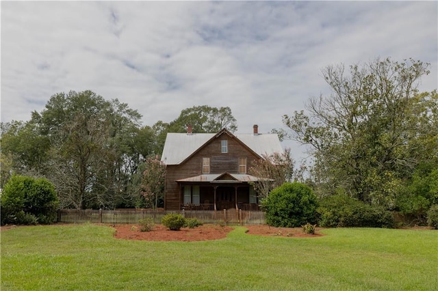 back of property with covered porch, a lawn, a chimney, and fence