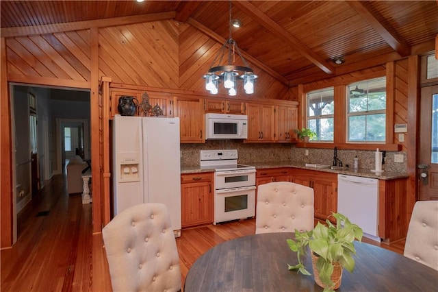 kitchen with wooden walls, decorative backsplash, light wood-style floors, white appliances, and a sink