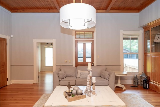 living area featuring light wood finished floors, a healthy amount of sunlight, and wooden ceiling