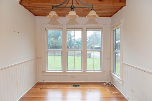 spare room with visible vents, wood ceiling, a wainscoted wall, and light wood-type flooring