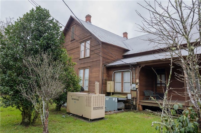 back of house featuring a lawn, central AC unit, and a chimney