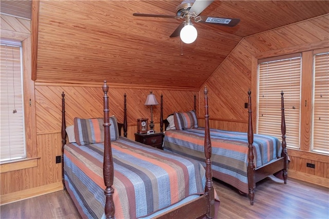 bedroom with wooden walls, wood finished floors, a ceiling fan, vaulted ceiling, and wood ceiling