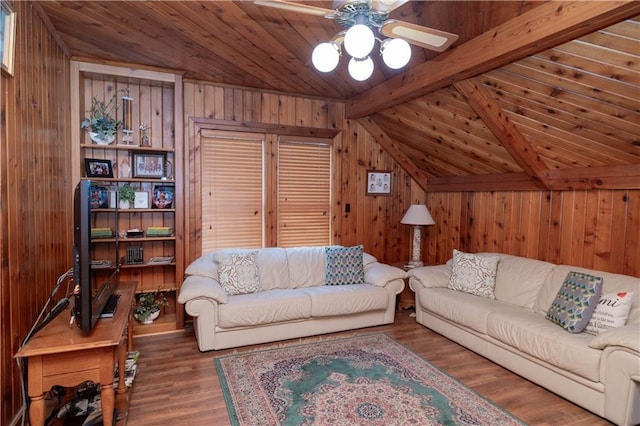 living area with a ceiling fan, wood finished floors, wooden walls, wood ceiling, and vaulted ceiling with beams