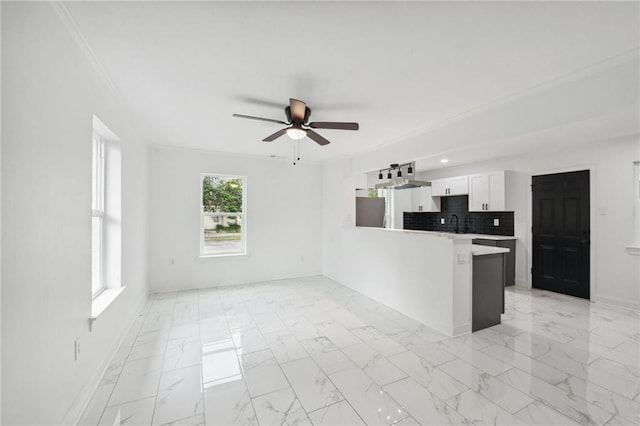 kitchen with white cabinetry, kitchen peninsula, ceiling fan, decorative backsplash, and ornamental molding