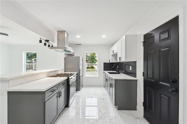 kitchen featuring wall chimney range hood, plenty of natural light, stainless steel appliances, and white cabinetry