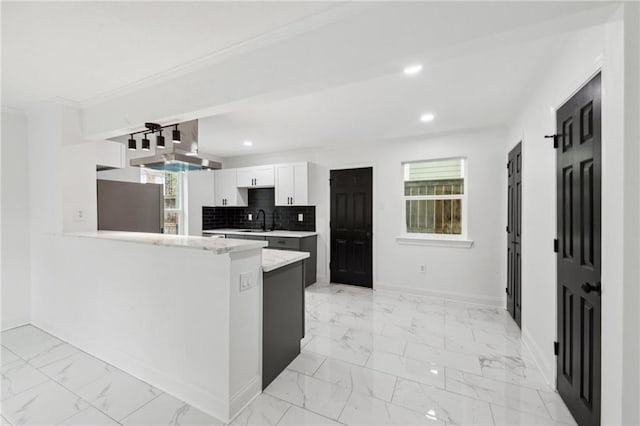 kitchen featuring stainless steel refrigerator, white cabinetry, kitchen peninsula, sink, and decorative backsplash