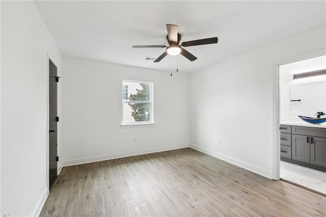 interior space with light hardwood / wood-style flooring, ceiling fan, sink, and connected bathroom