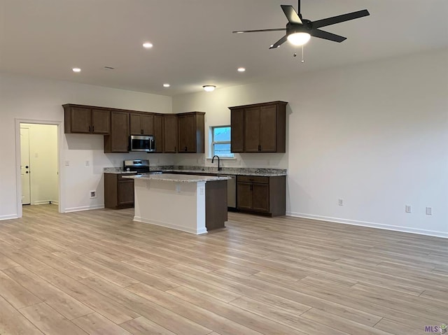 kitchen featuring sink, light hardwood / wood-style flooring, light stone countertops, a kitchen island, and stainless steel appliances