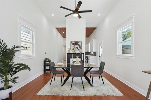 dining space featuring a towering ceiling, wood-type flooring, and ceiling fan