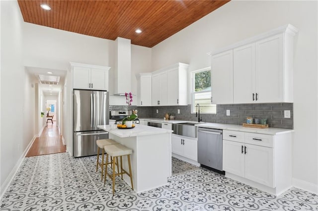 kitchen featuring stainless steel appliances, a kitchen breakfast bar, a kitchen island, sink, and wooden ceiling