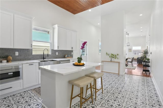 kitchen with oven, sink, a center island, and white cabinets