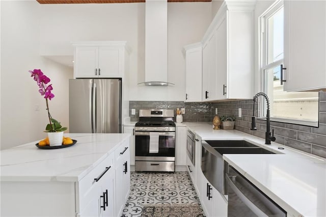 kitchen featuring appliances with stainless steel finishes, white cabinetry, backsplash, and light stone countertops