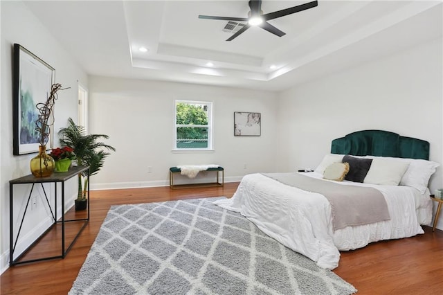 bedroom featuring a raised ceiling, ceiling fan, and hardwood / wood-style floors