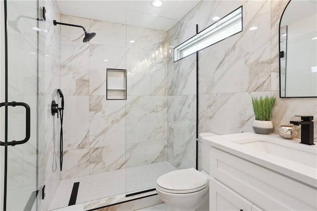 bathroom featuring a shower with door, vanity, toilet, and tile walls