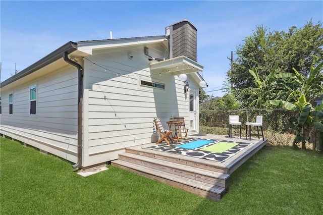 rear view of house with a lawn and a wooden deck