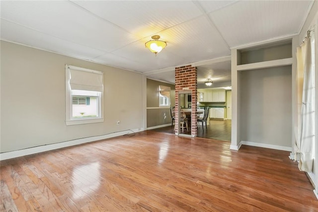 unfurnished living room with wood-type flooring and a brick fireplace