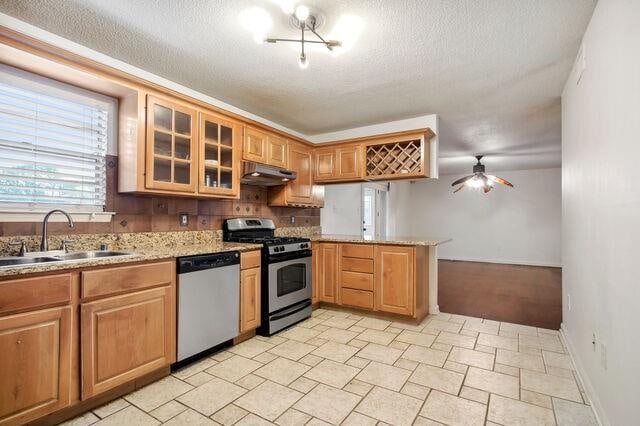 kitchen with a textured ceiling, appliances with stainless steel finishes, sink, and kitchen peninsula