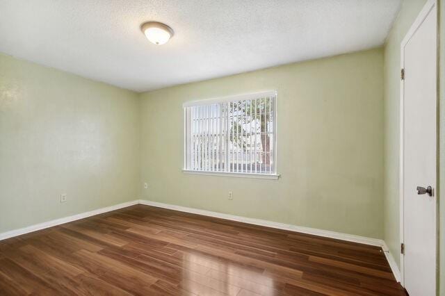 unfurnished room featuring a textured ceiling and dark wood-type flooring