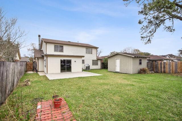 rear view of house featuring a patio, a shed, and a yard