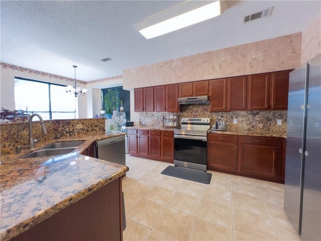 kitchen with appliances with stainless steel finishes, pendant lighting, sink, decorative backsplash, and light stone countertops