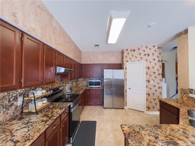 kitchen featuring stone counters, appliances with stainless steel finishes, light tile patterned floors, and backsplash