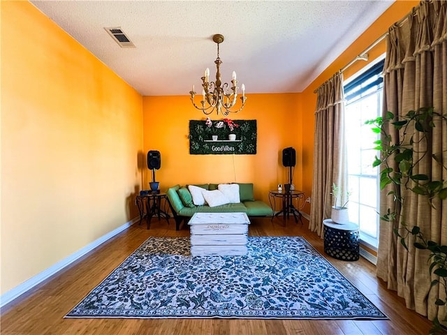 sitting room featuring wood-type flooring, a notable chandelier, and a textured ceiling