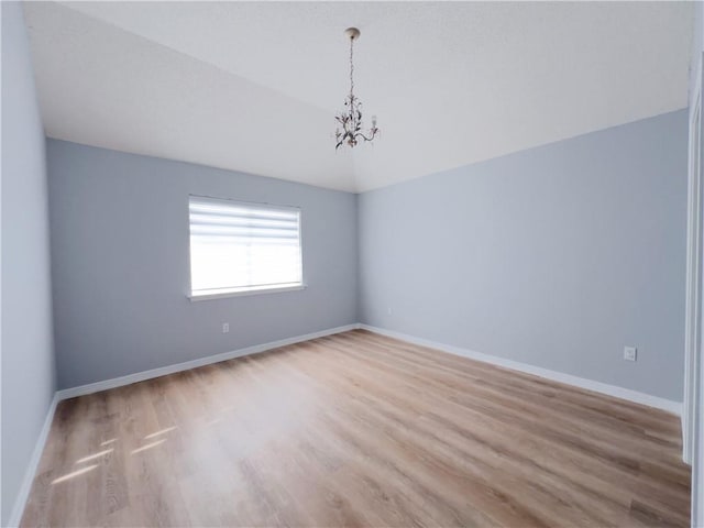 empty room featuring a notable chandelier and light hardwood / wood-style flooring