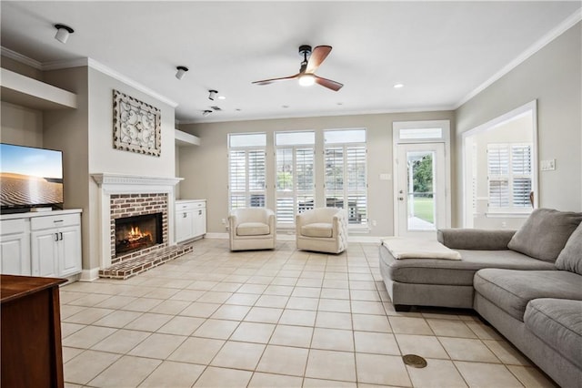 living room with a fireplace, a ceiling fan, ornamental molding, and light tile patterned flooring