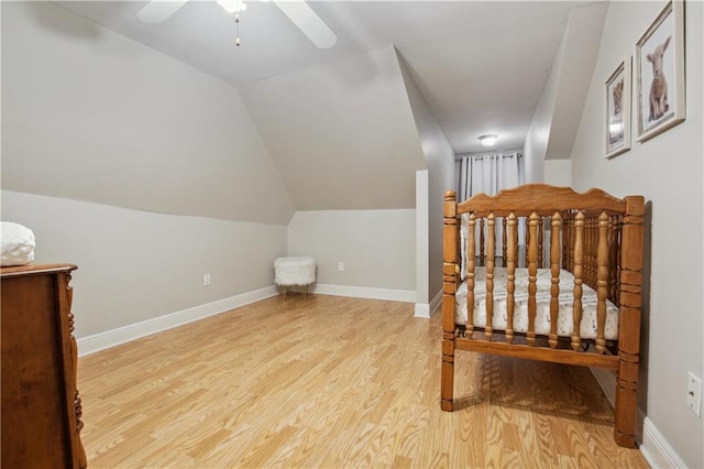 bedroom featuring light wood finished floors, baseboards, a ceiling fan, and lofted ceiling
