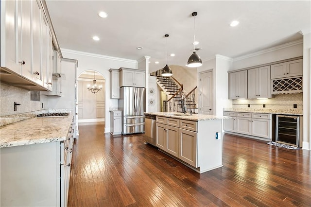 kitchen with dark hardwood / wood-style floors, wine cooler, hanging light fixtures, stainless steel appliances, and a center island