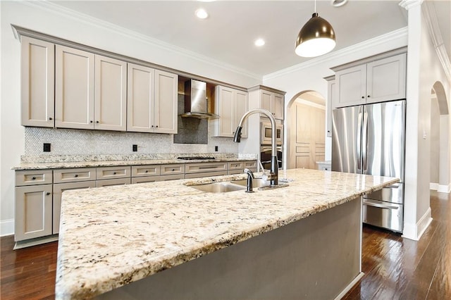 kitchen with decorative light fixtures, light stone counters, stainless steel appliances, and wall chimney exhaust hood