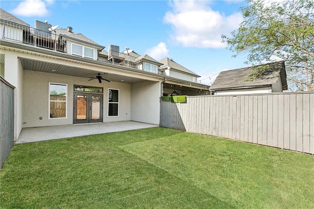 rear view of house featuring a balcony, ceiling fan, a lawn, and a patio