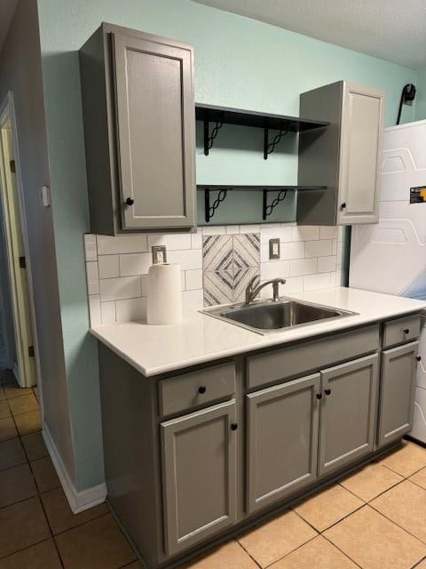 kitchen featuring gray cabinets, sink, backsplash, and light tile patterned floors