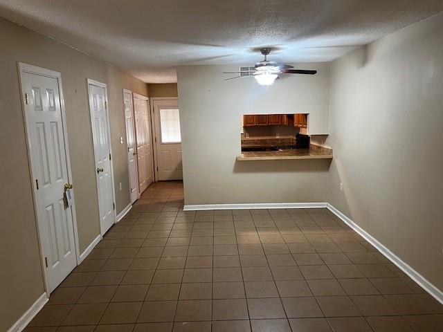 tiled foyer entrance featuring a textured ceiling and ceiling fan