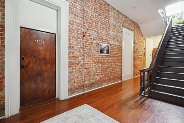 interior space featuring brick wall and dark hardwood / wood-style floors