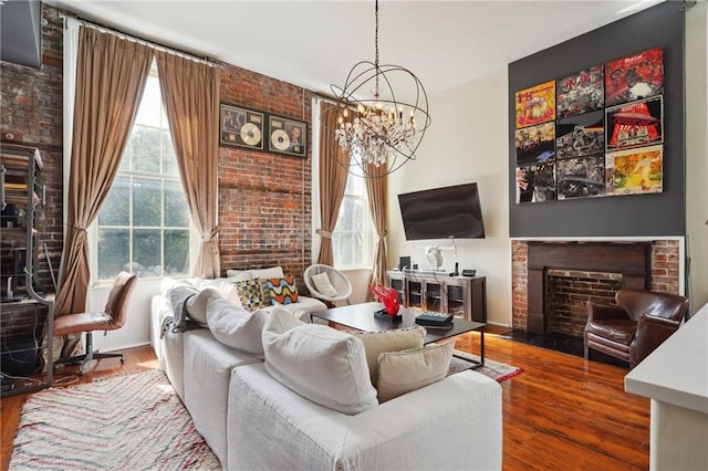 living room with hardwood / wood-style flooring, an inviting chandelier, and brick wall