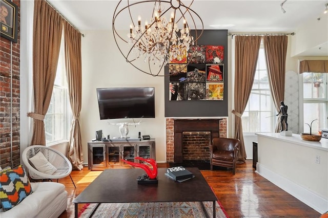 living room with a fireplace, wood-type flooring, and an inviting chandelier