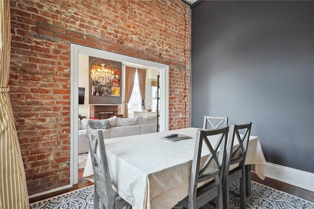 dining space featuring brick wall, a notable chandelier, and hardwood / wood-style floors