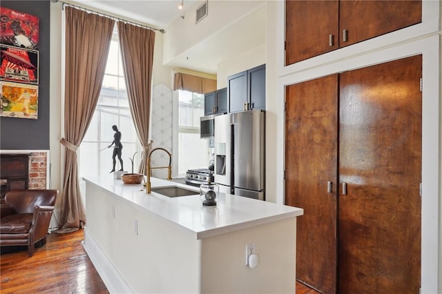 kitchen with dark wood-type flooring, stainless steel appliances, kitchen peninsula, and sink