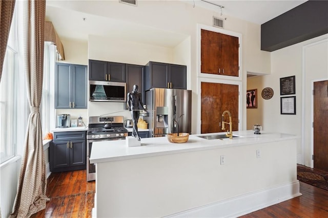 kitchen with stainless steel appliances, sink, dark hardwood / wood-style floors, and a kitchen island with sink