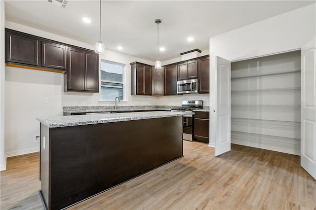 kitchen featuring light stone counters, a kitchen island, appliances with stainless steel finishes, light hardwood / wood-style floors, and decorative light fixtures