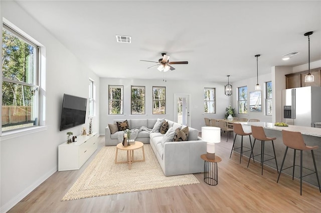 living room featuring ceiling fan, light hardwood / wood-style floors, and plenty of natural light