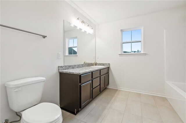 bathroom with toilet, a healthy amount of sunlight, vanity, and tile patterned floors