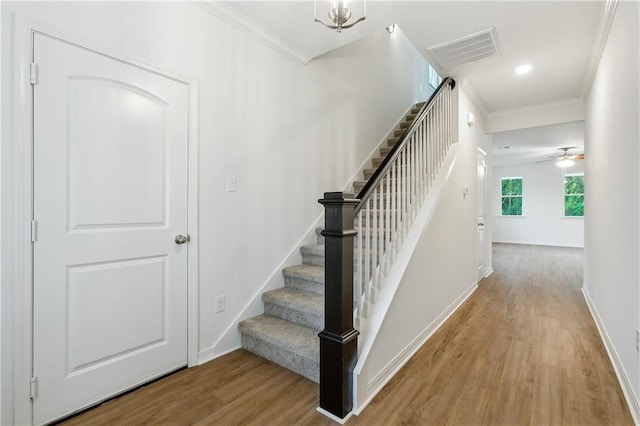 stairway featuring ceiling fan, ornamental molding, and hardwood / wood-style floors