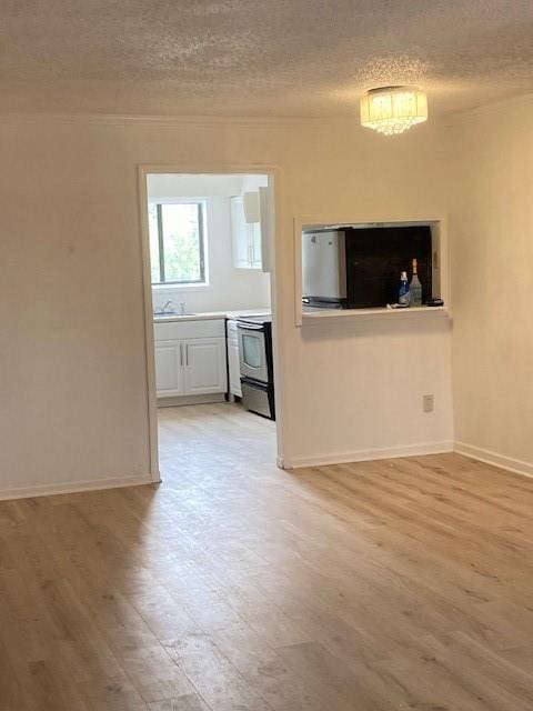 unfurnished living room with light wood-type flooring, sink, and a textured ceiling