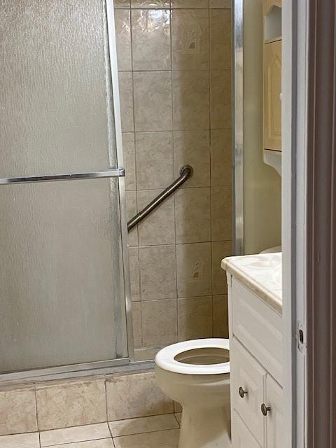 bathroom with vanity, toilet, an enclosed shower, and tile patterned floors