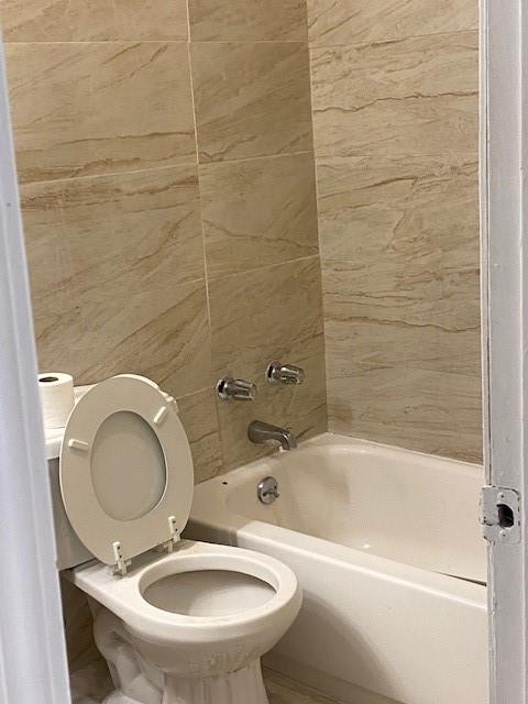 bathroom featuring toilet and tiled shower / bath combo