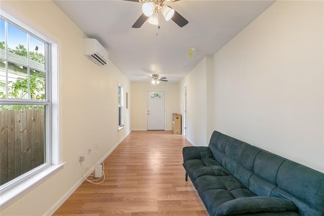 living room with ceiling fan, light wood-type flooring, and a wall unit AC