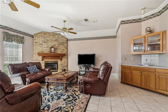 tiled living room featuring ceiling fan, lofted ceiling, a brick fireplace, and sink