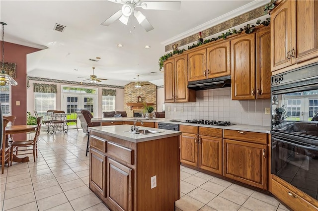 kitchen featuring ceiling fan, a kitchen island with sink, and decorative light fixtures